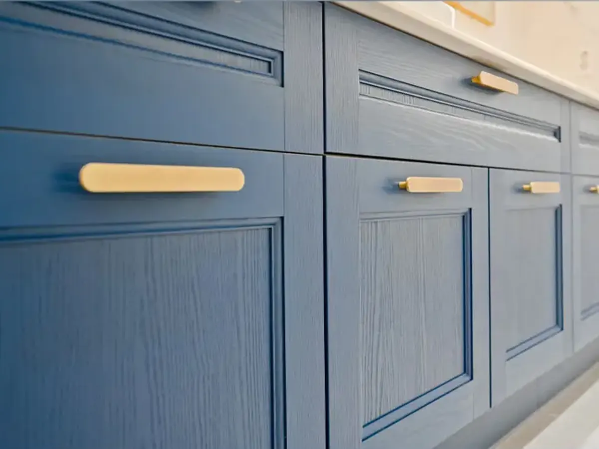 Portas e gavetas de cozinha laqueadas em azul, com frisos e puxadores dourados